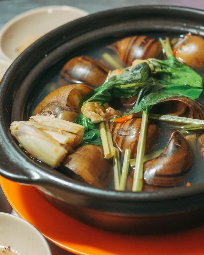 Nồi ốc nấu sả, lá thơm và chén nước chấm