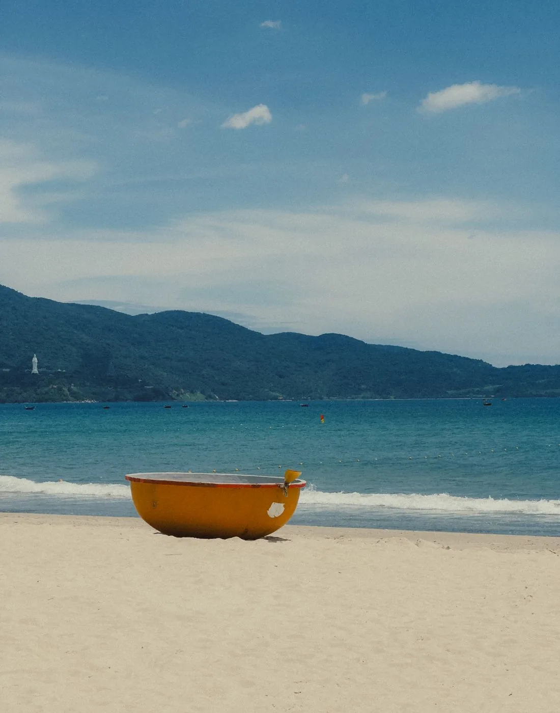 Chiếc thúng chai vàng trên bãi cát, phía sau là bán đảo Sơn Trà